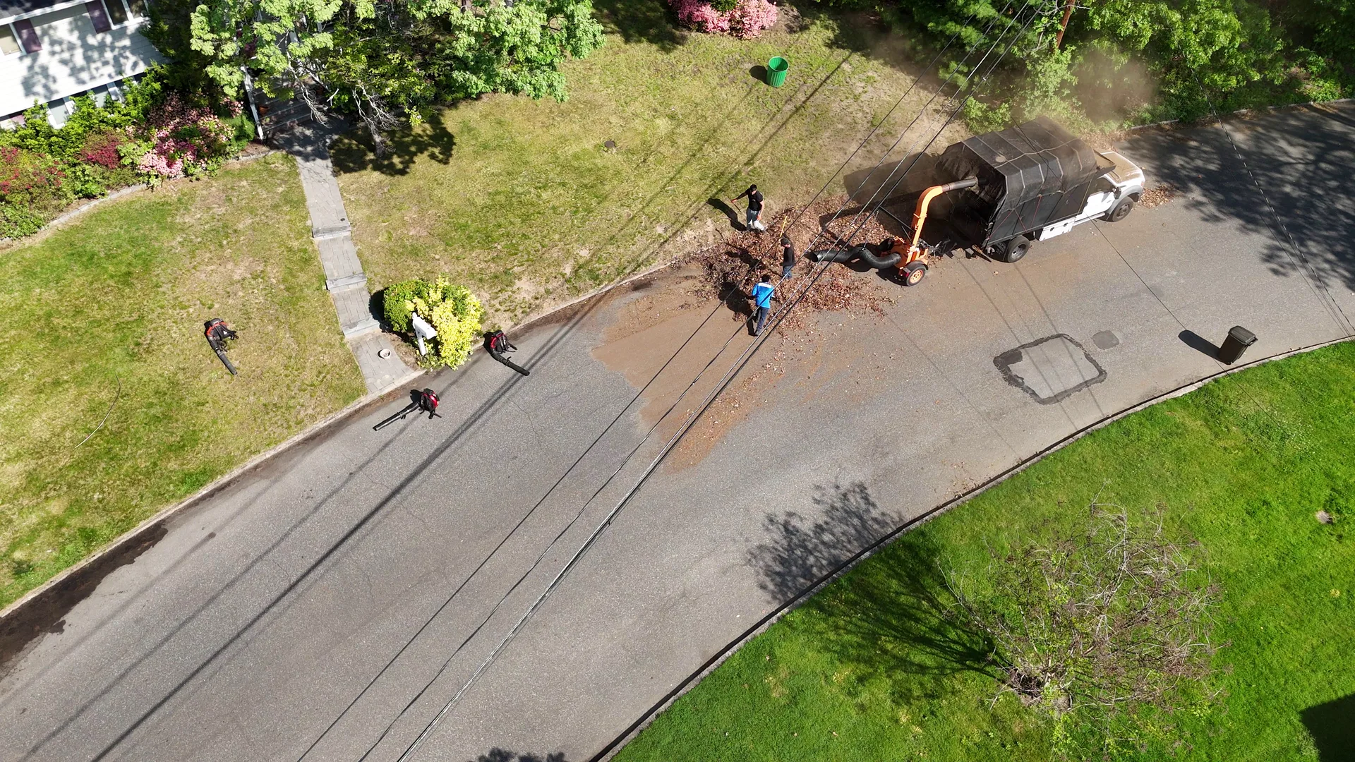 Aerial of the crew and trucks staged along a suburban street during a big property cleanup.