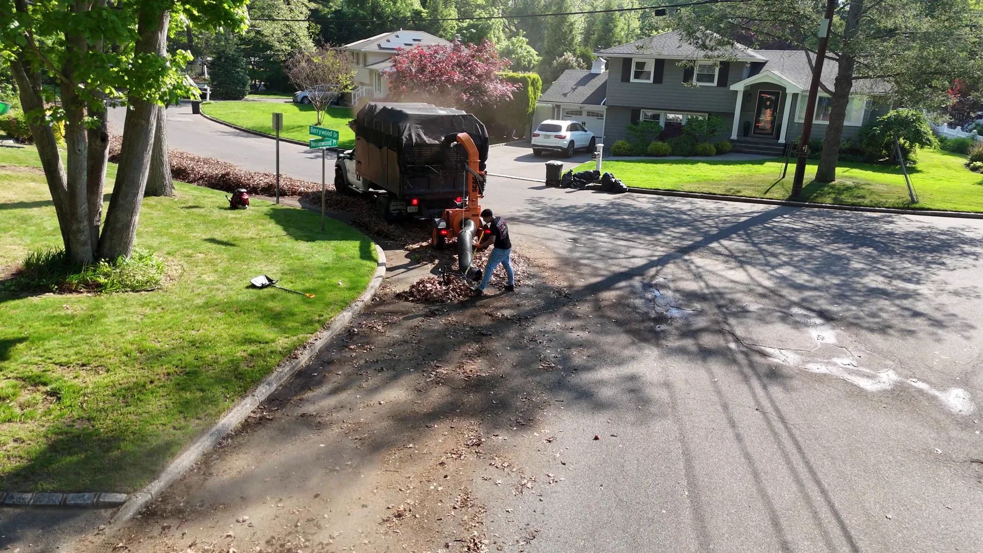 A Satiscapes truck in a driveway with full tarps of leaves loaded during a fall property cleanup.