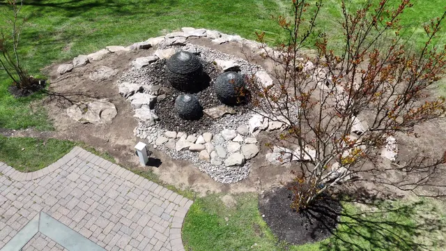Aerial of a stone fountain being set into a new flagstone patio, mid-installation.